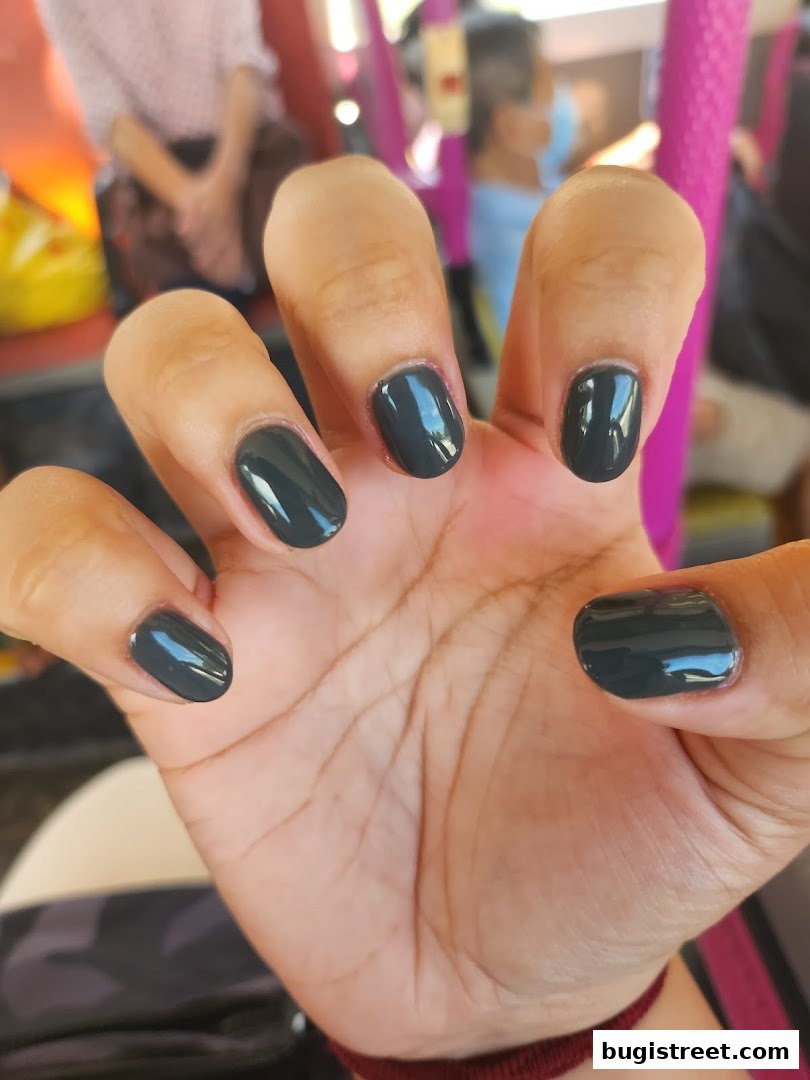 A close-up of a hand with neatly painted dark grey nails.