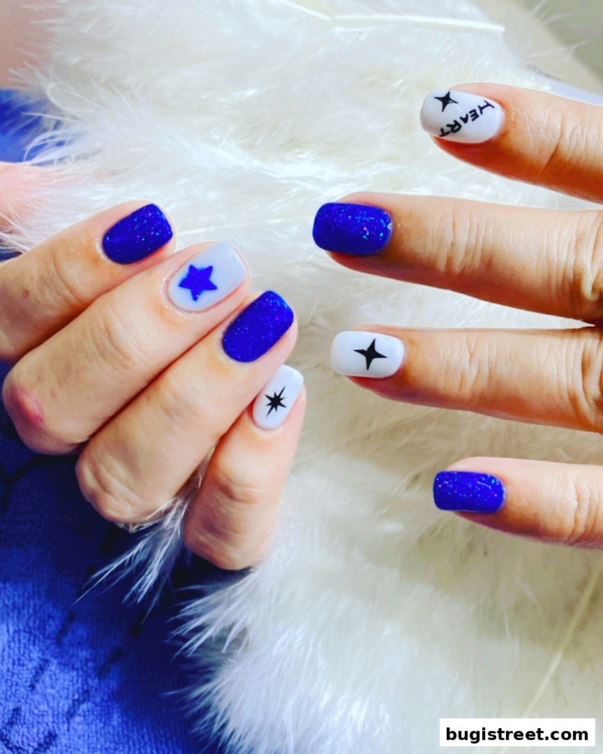 Close-up of hands with beautifully designed blue and white nails featuring stars and text.
