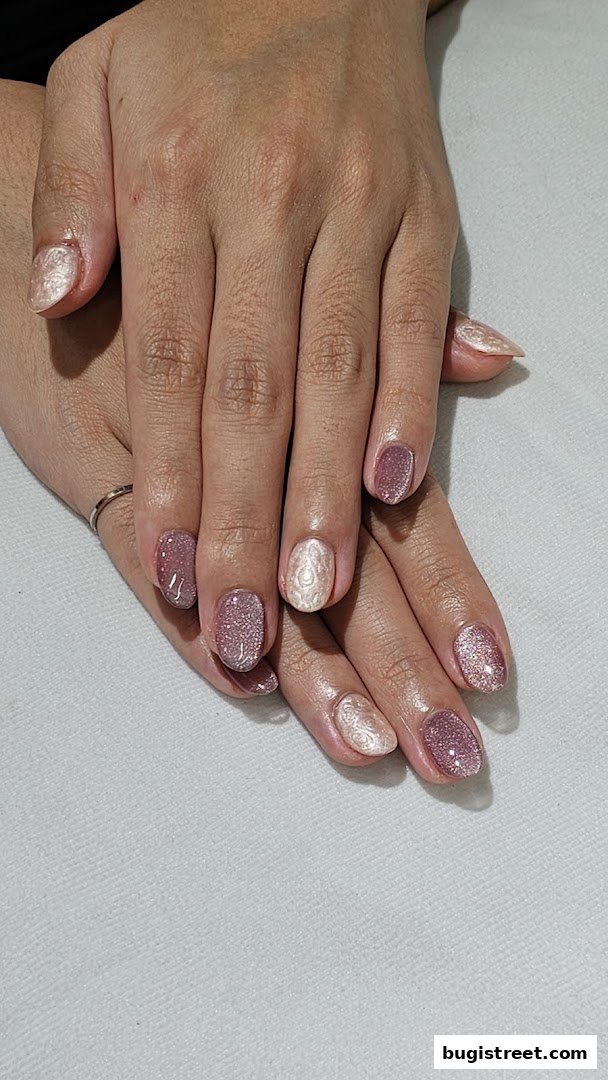 Close-up of hands with beautifully manicured nails featuring glitter and intricate designs.