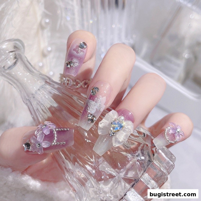Close-up of a hand with elaborately decorated nails featuring rhinestones and floral embellishments.