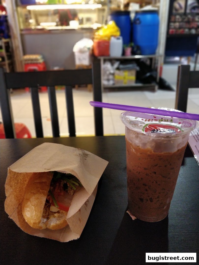 A sandwich and a drink with a purple straw on a table at Shoon Kou Cafe.