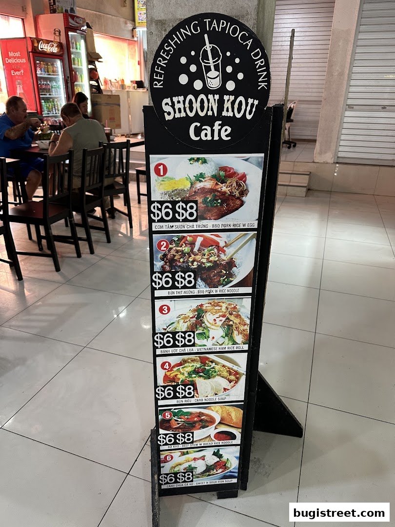 A menu board for Shoon Kou Cafe displays various Vietnamese dishes with prices.