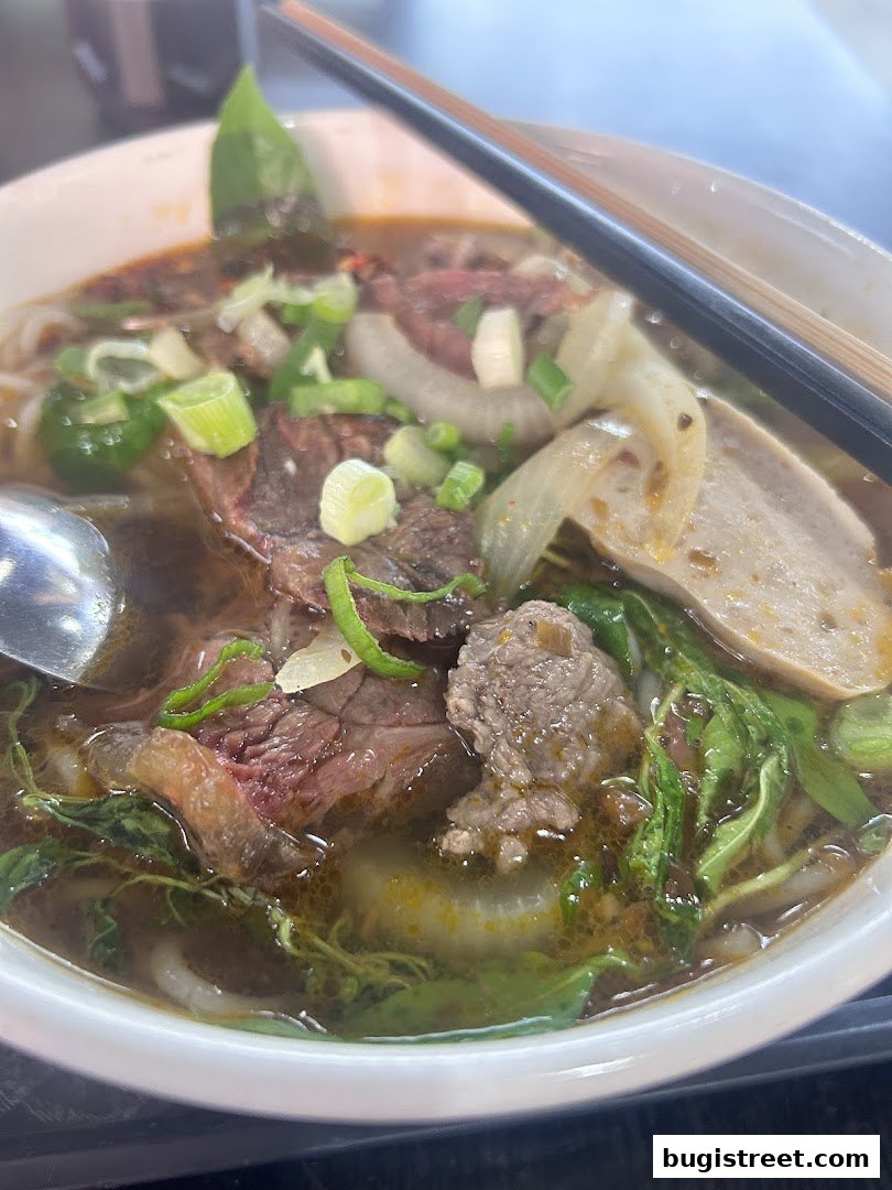 A close-up shot of a steaming bowl of pho with beef, noodles, and herbs.