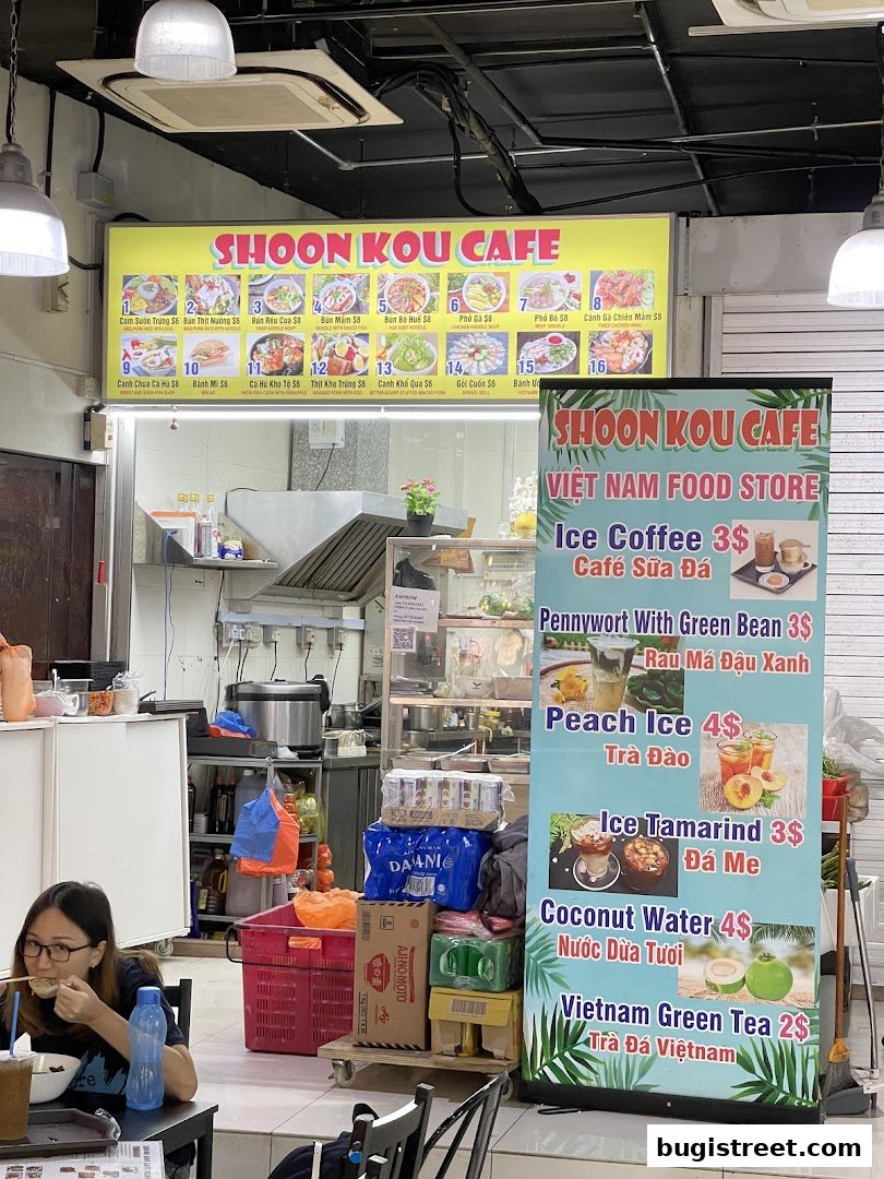 A Vietnamese food store with a menu board and a promotional banner displaying drinks.