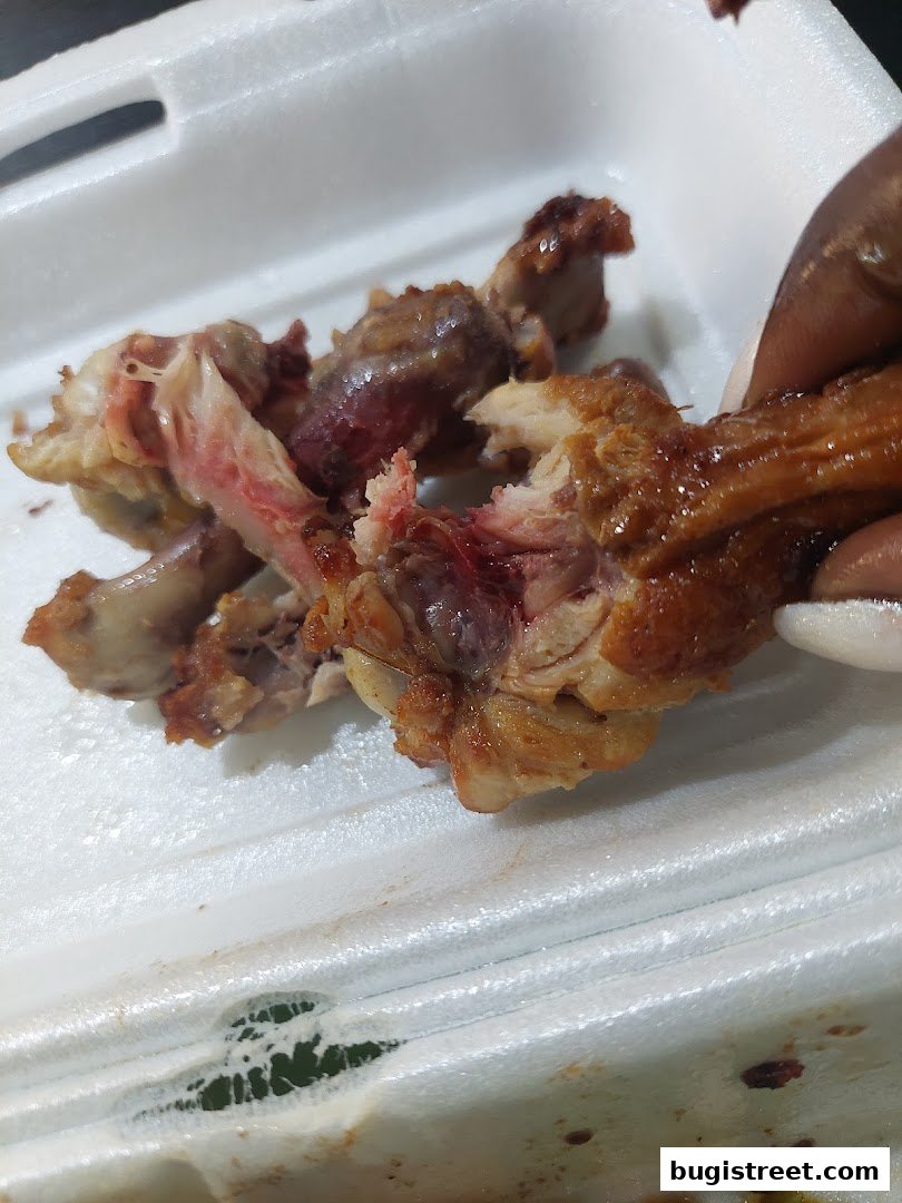 Close-up of cooked chicken wings with visible bones and meat in a white container.