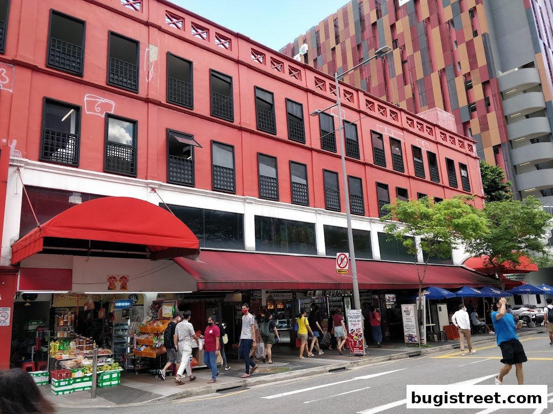 A vibrant red building with multiple shops and awnings on a sunny day.