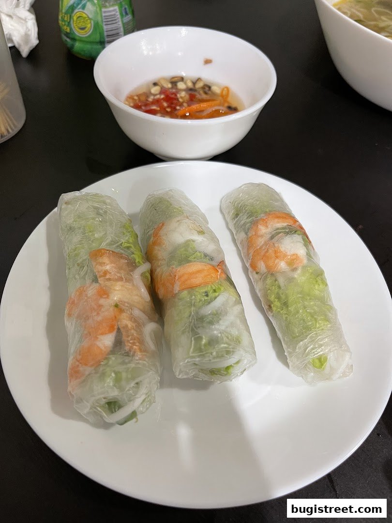 Three fresh spring rolls with shrimp and vegetables served with dipping sauce.