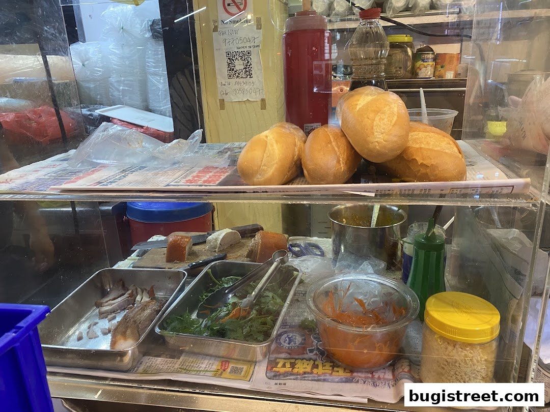 A display case filled with fresh bread, meats, and salad ingredients for sandwiches.