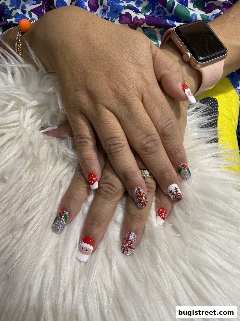 Close-up of hands with festive Christmas-themed nail art, including Santa, reindeer, and snowflakes.