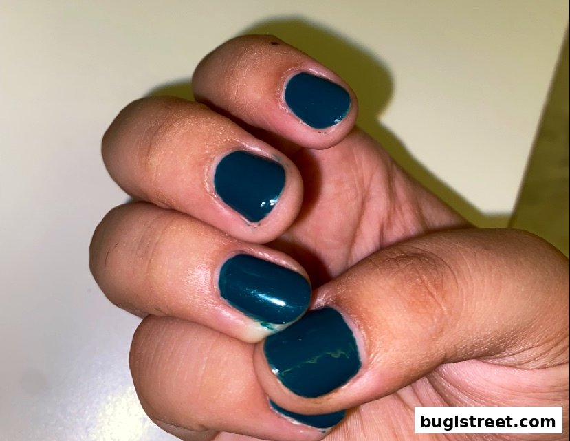 A close-up shot of a hand with dark teal nail polish.