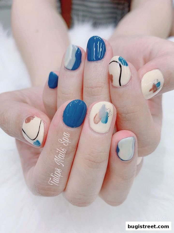 Close-up of hands with abstract art-inspired nail designs in blue, cream, and brown.