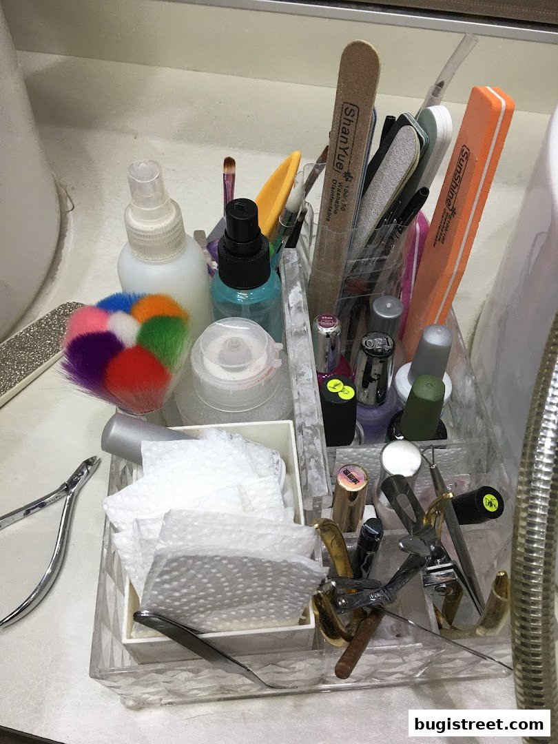 A close-up of a nail technician's tools and supplies organized in a clear acrylic caddy.