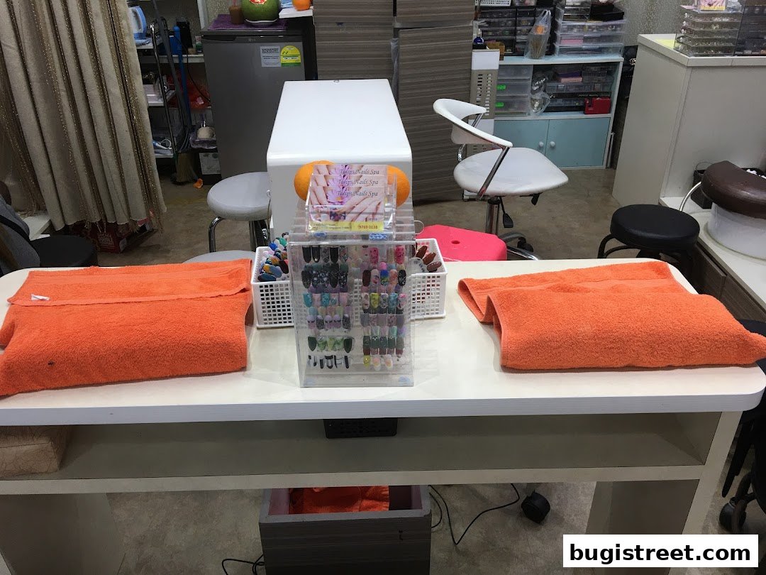 A nail spa table with orange towels, nail polish display, and chairs.