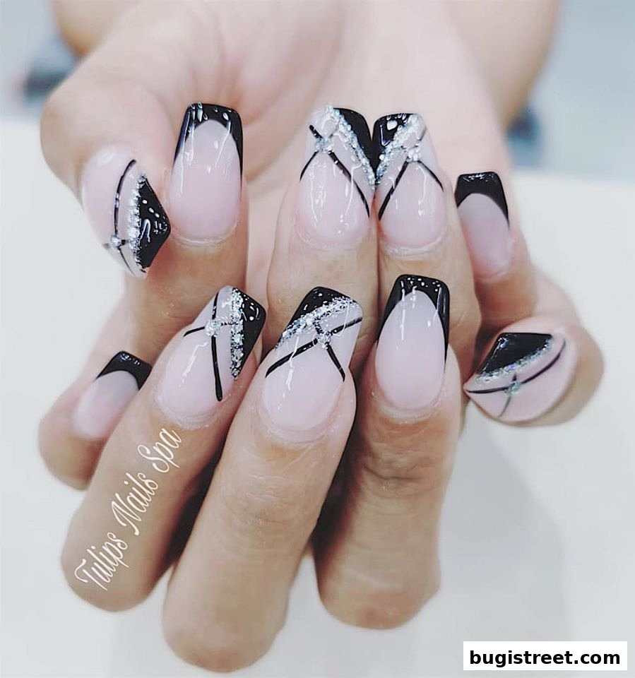 A close-up of a hand showcasing stylish French tip nails with black and silver geometric designs.