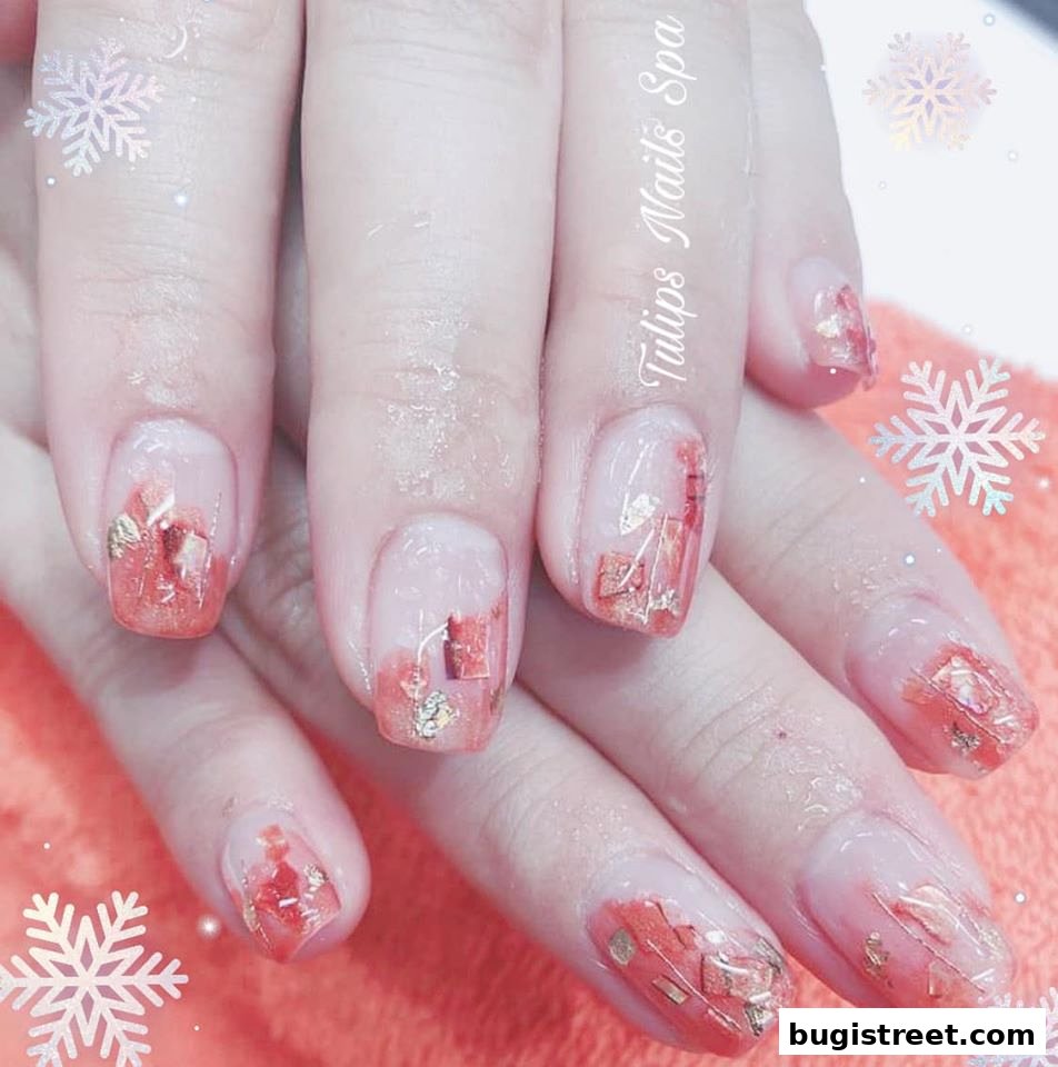 Close-up of hands with beautifully decorated nails featuring a clear base with orange and gold accents.