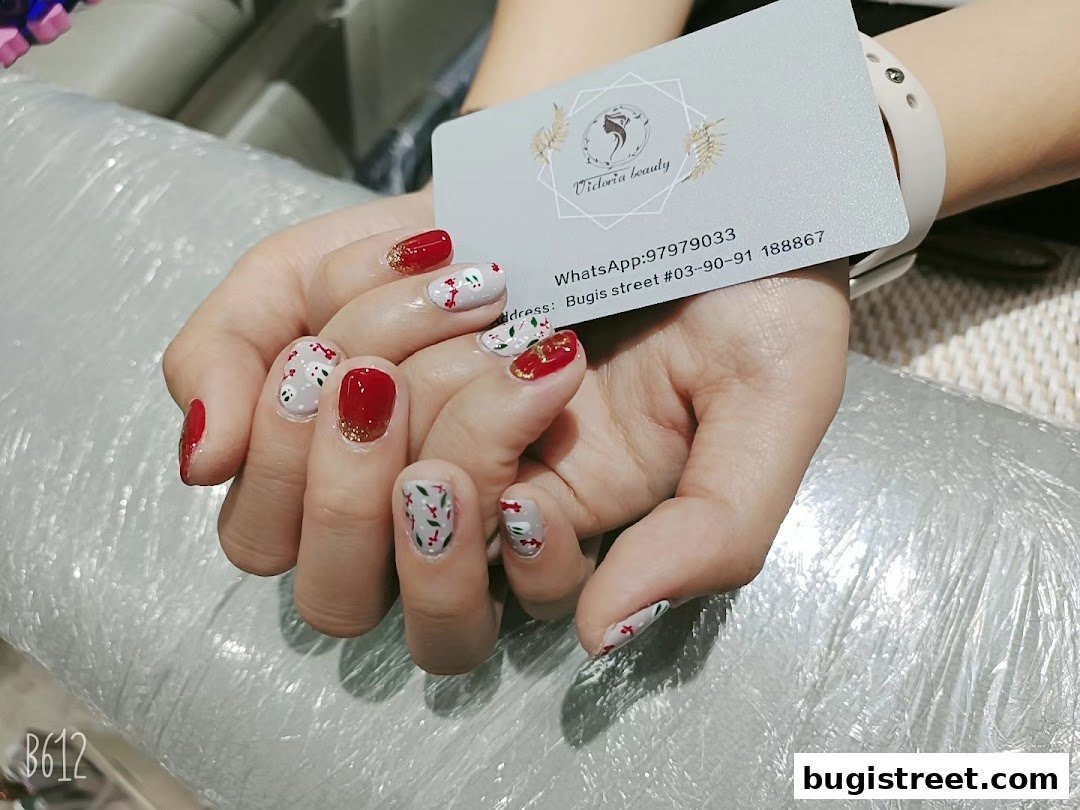 A close-up of hands with festive red and white nail art, holding a business card.