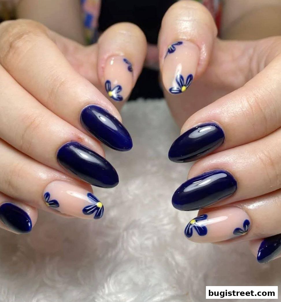 Close-up of hands with elegant dark blue and floral nail art.