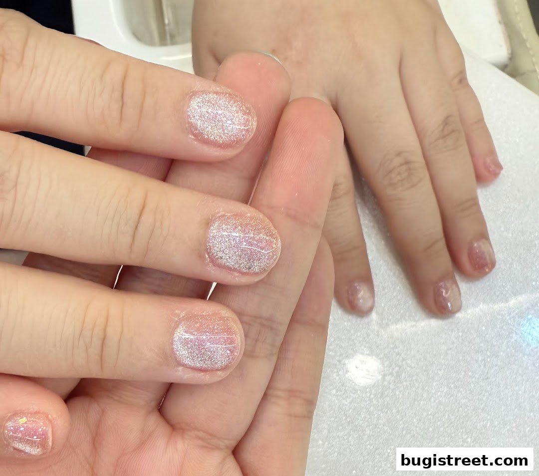 Close-up of hands with beautifully manicured nails featuring a subtle glitter effect.
