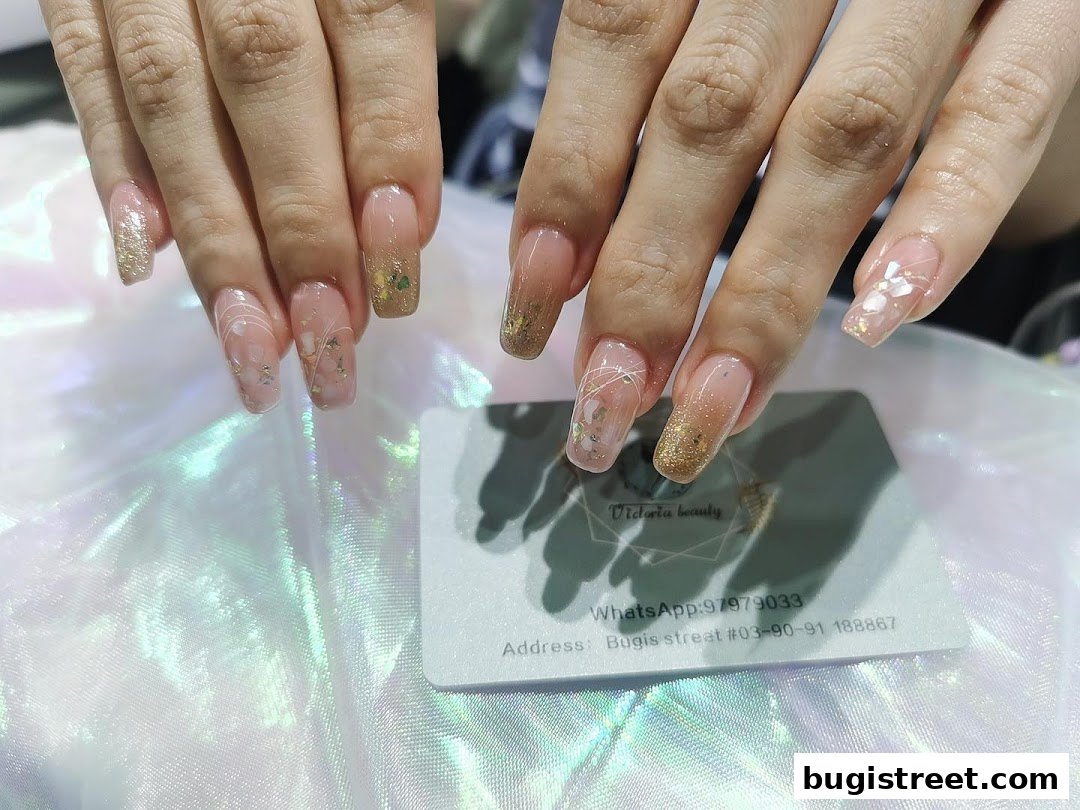 Close-up of beautifully designed nails with glitter and floral accents, next to a business card.