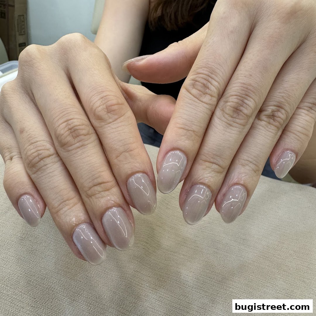 Close-up of a person's hands with elegant, neutral-toned gel manicured nails.